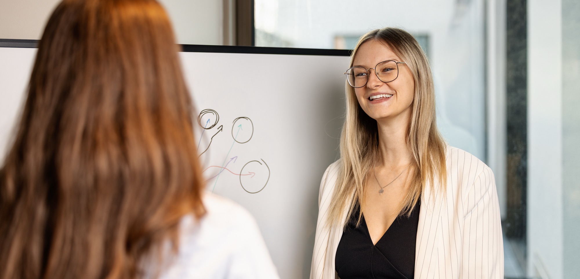 Projektleiterin skizziert am Whiteboard die Vermarktungsstrategie für Immobilienmarketing Berlin